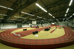 An Indoor Track with rust colored lanes and equipment at its center
