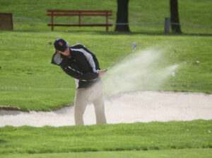 Boys Golfer hitting a ball out of sand pit